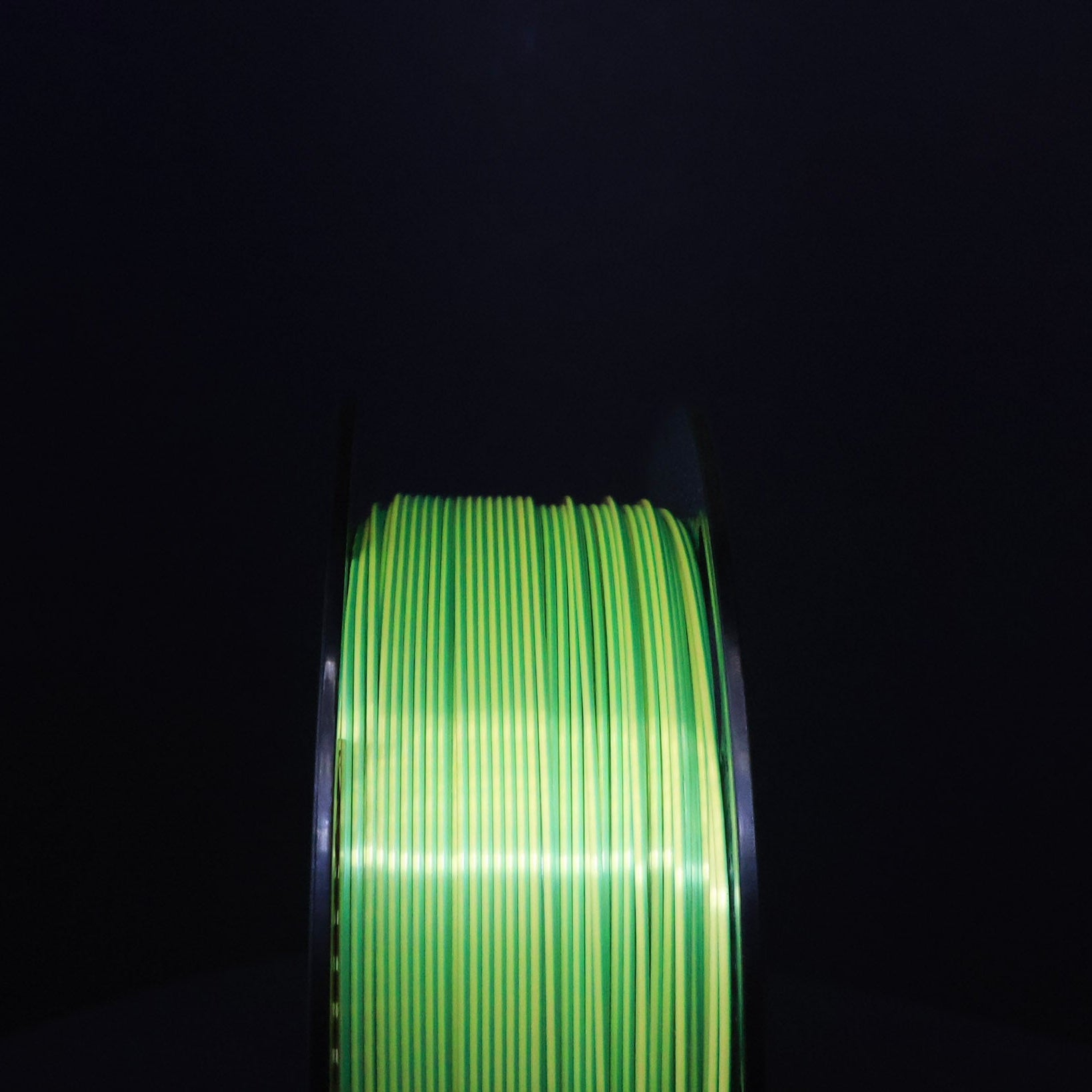 Spool of green filament on a black background