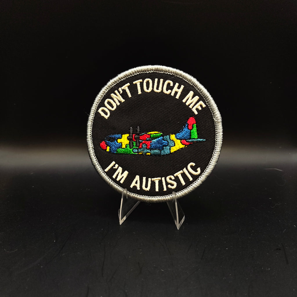 Patch with 'Don't Touch Me I'm Autistic' text and colorful symbols on a black background