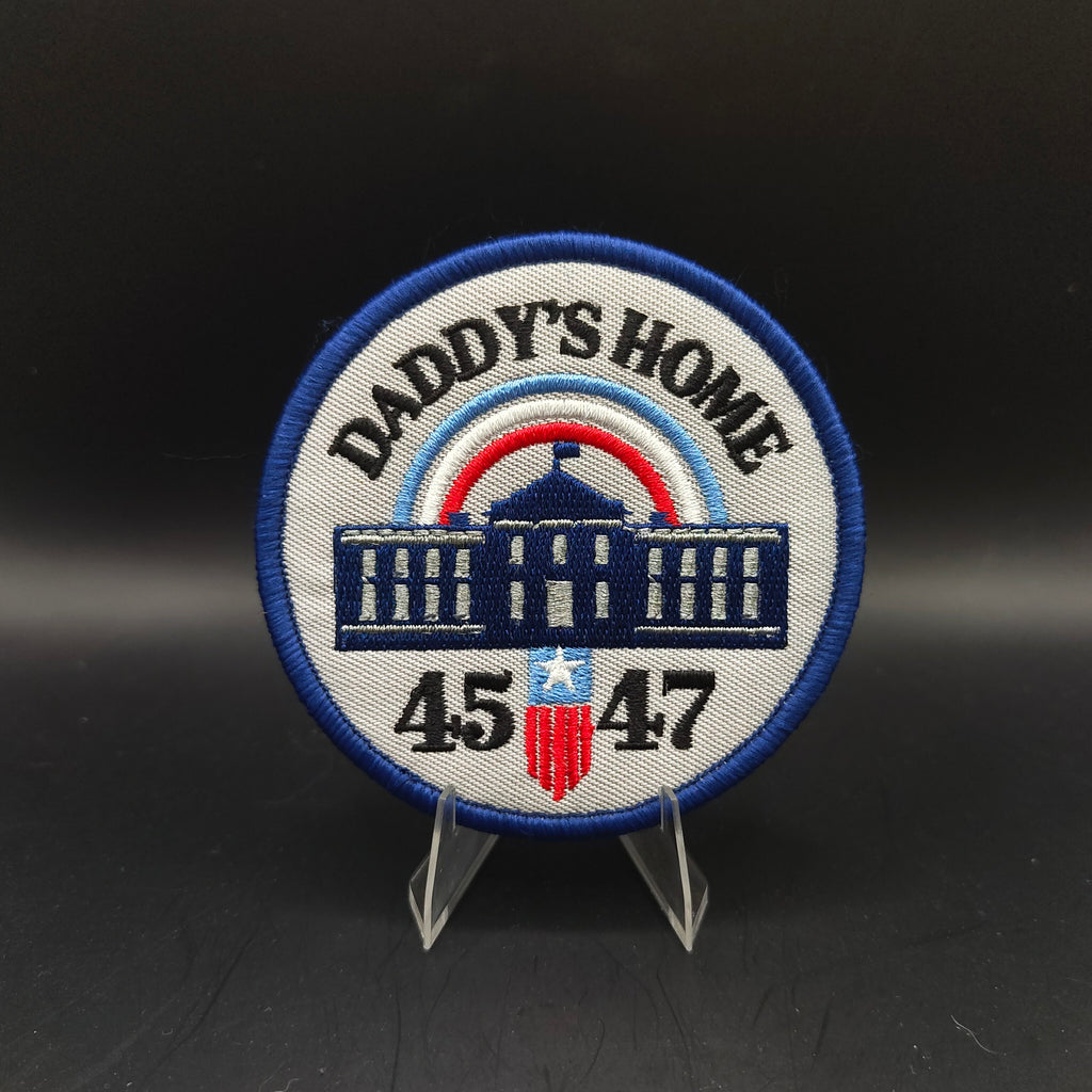 Patch with 'Daddy's Home' text and numbers on a stand against a dark background Trump Patch 45 47