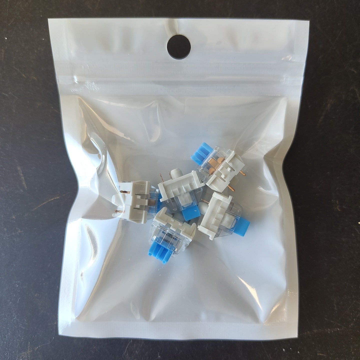 Mechanical keyboard switches in a clear plastic bag on a dark surface